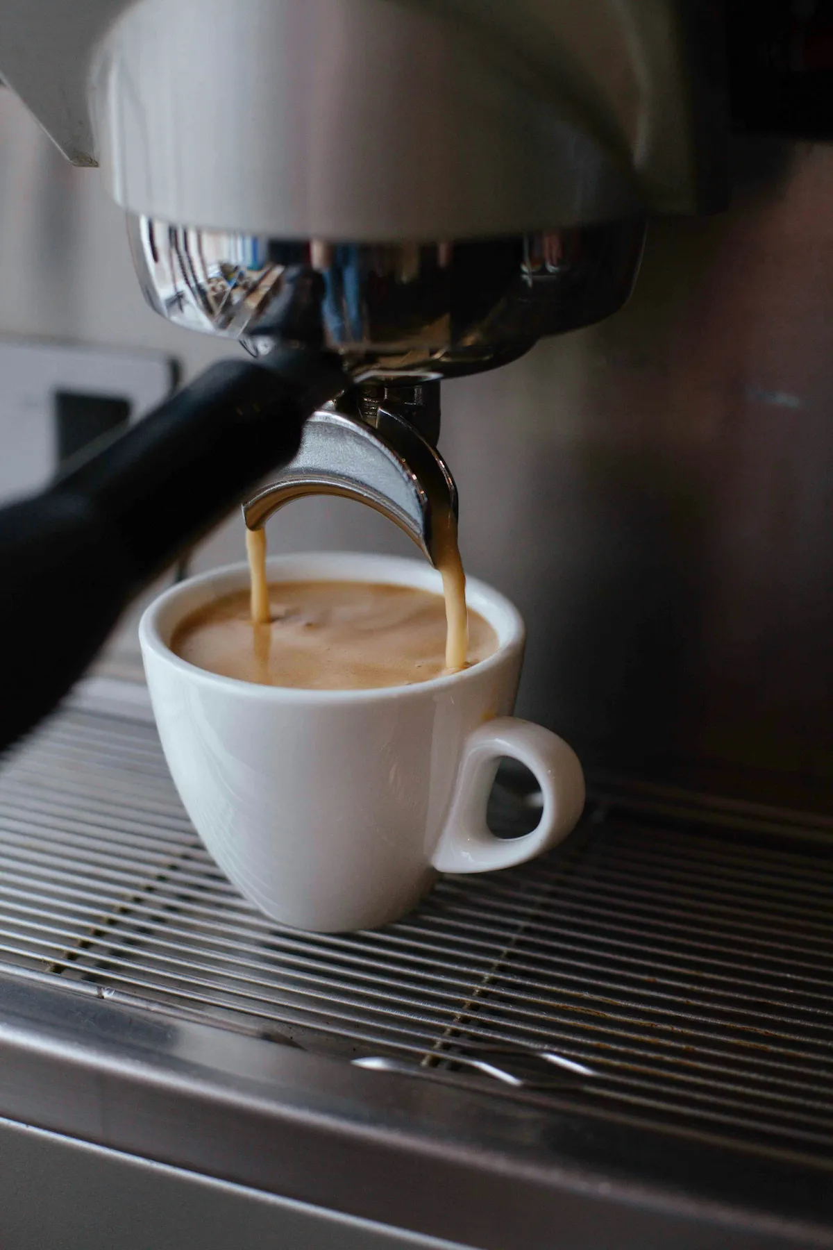 Fresh espresso being poured into a ceramic cup.